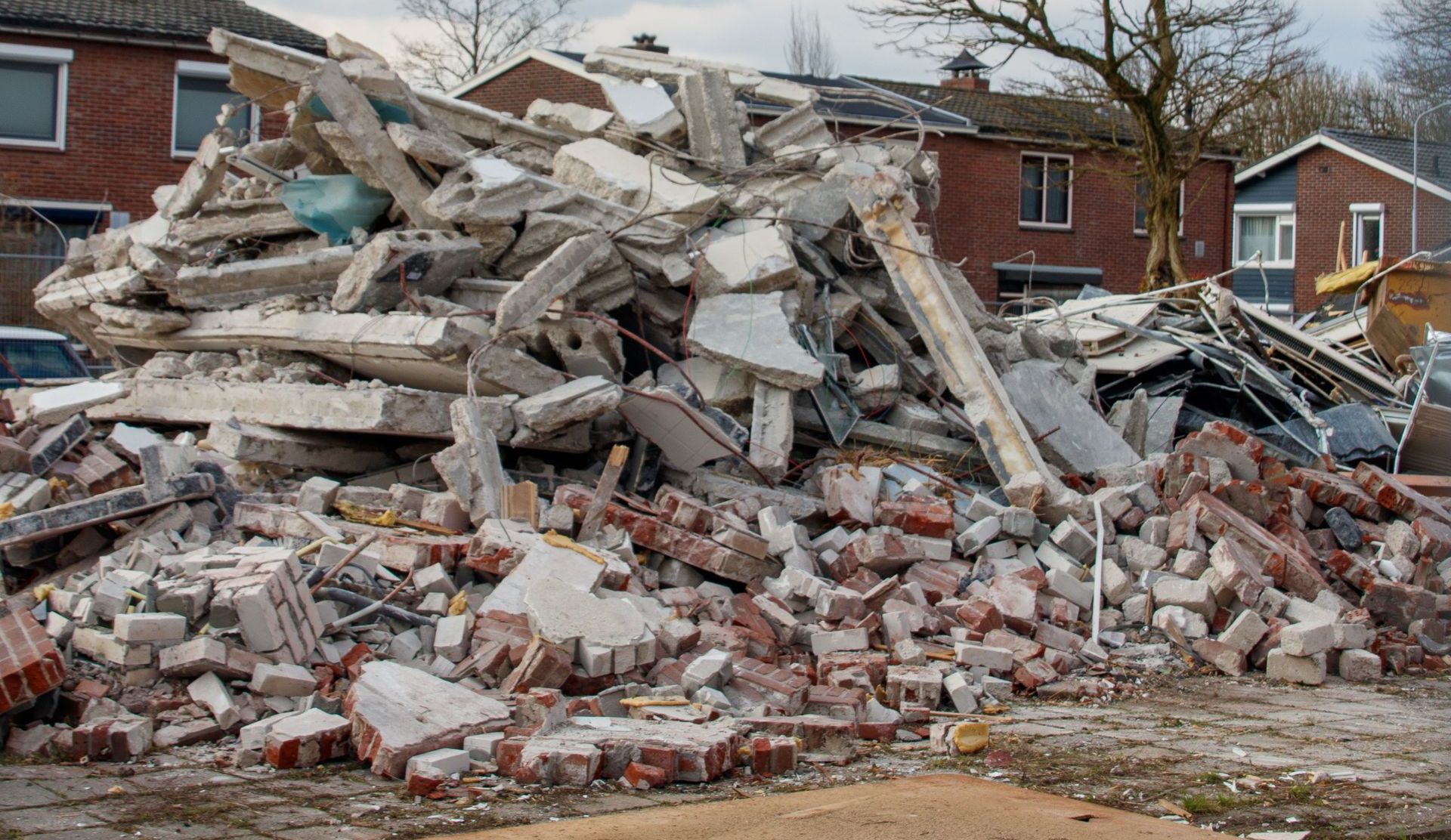Piles of concrete and bricks from demolished buildings in a residential area.